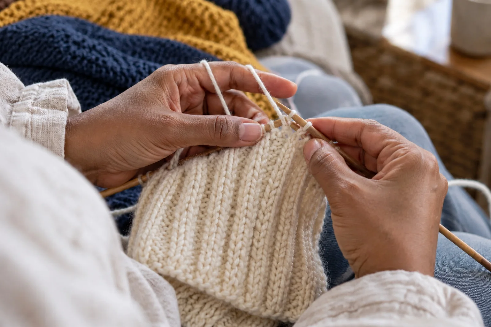 Close-up of hands knitting an ivory piece on bamboo needles